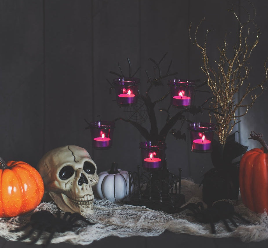 Halloween-themed setup with pumpkins, skull, and candles on a dark background